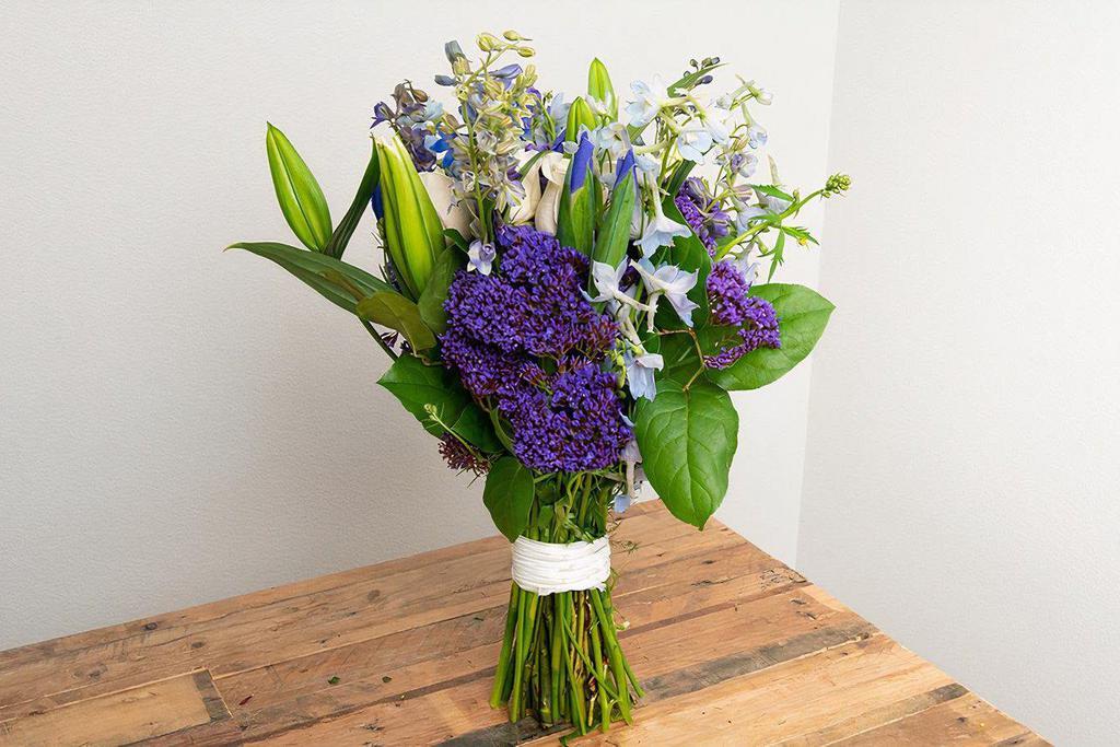 White, Blue, Purple Wrapped Bouquet · Seasonal options may vary throughout the year and depending on location. Our florist will provide the best available flowers for your order!