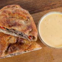 Philly Cheesesteak Calzone · Roast beef, mozzarella, bell peppers, mushrooms, & caramelized onions, house cheese whiz sau...