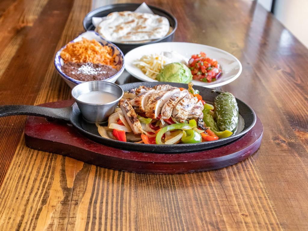 Fajitas · Mesquite grilled, served sizzling with grilled onions, bell peppers, frothy garlic butter. All fajitas include guacamole, pico de gallo, mexi-quesos, sour cream, Spanish or cilantro brown rice, beans, cheese and your choice of flour or corn tortillas (large combo pictured)