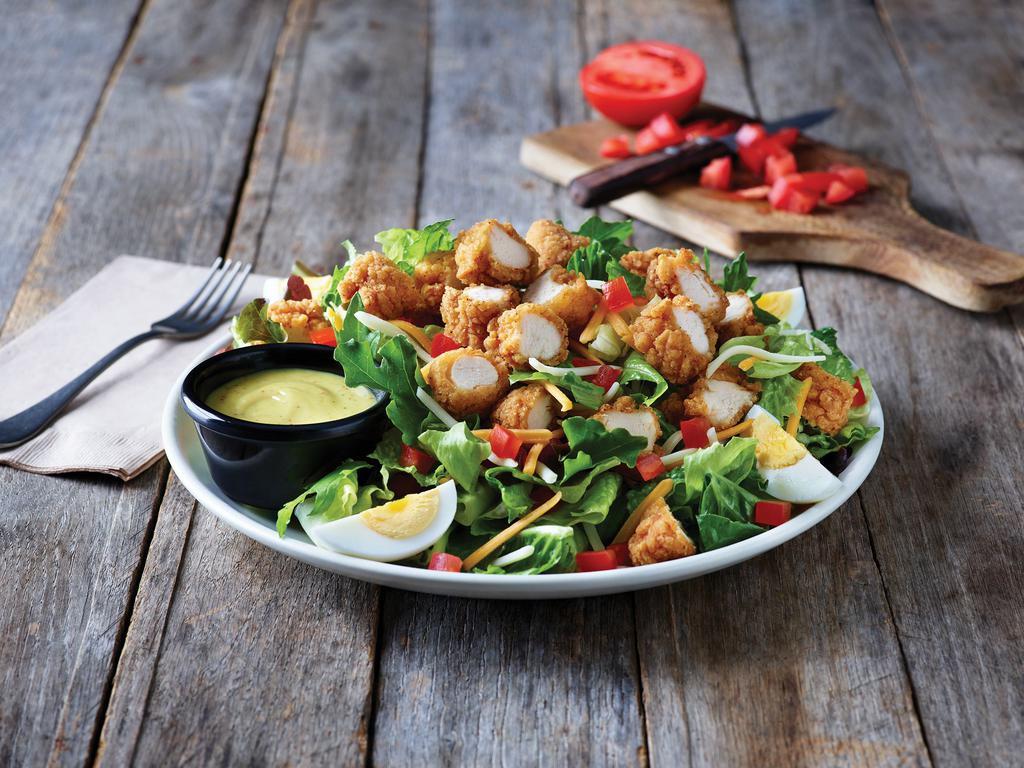 Crispy Chicken Tender Salad · A hearty salad with crispy chicken tenders on a bed of fresh greens topped with a blend of Cheddar cheeses, tomatoes and a hard-boiled egg. Served with honey Dijon mustard dressing.