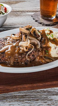 The Big Fatz Chopped Steak · Generous 14 oz. chopped steak, fire-grilled, and smothered with roasted mushrooms and onions in merlot au jus. Served with red-skinned mashed potatoes and choice of house or Caesar salad.
