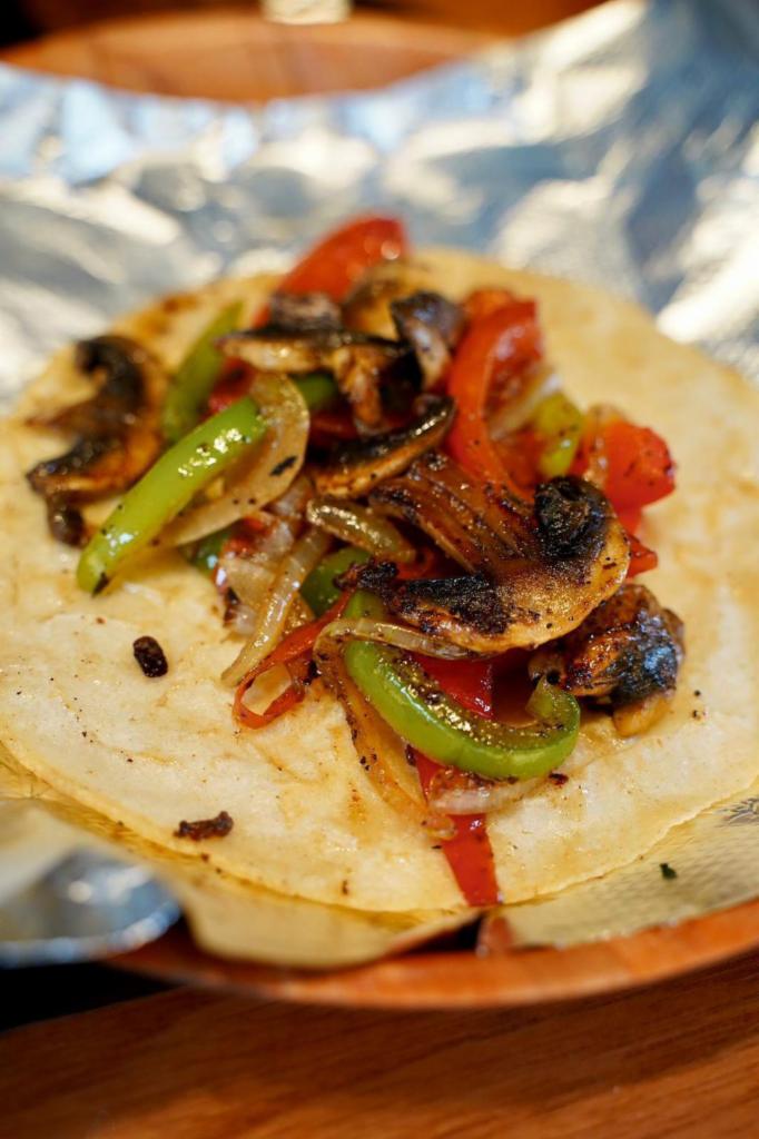 Vegetariano Taco · Seasoned grilled bell peppers, onions, and mushrooms over handmade corn tortilla. Combinacion de vegetales como pimiento morron, champinones, y cebolla a sazonados a la plancha sobre tortilla de maiz hecha a mano. 
