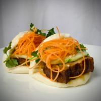 Pork Belly Bao · Two pieces of braised pork belly bao with cucumber slices, carrots, cilantro, crushed peanut.
