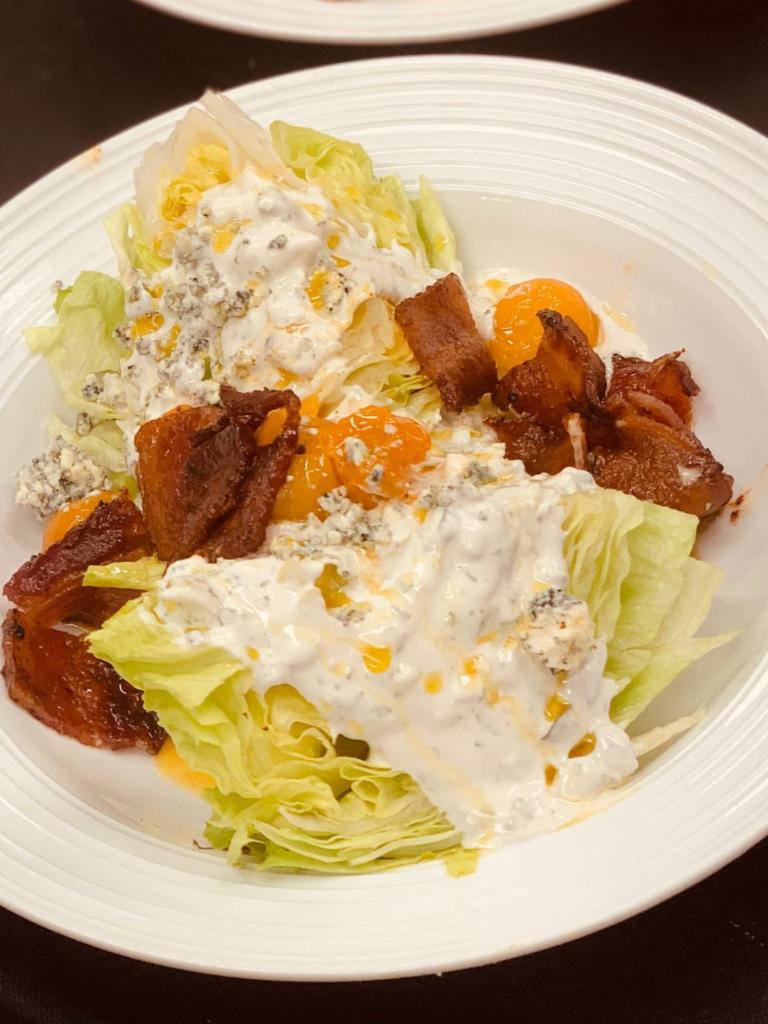 Chopped Wedge Salad · Candied bacon, chive oil, confit tomatoes, crumbled bleu cheese, bleu cheese dressing.