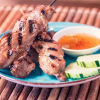 Moo Ping · Thai street-food style marinated pork, skewered and grilled.  Served with our spicy homemade...