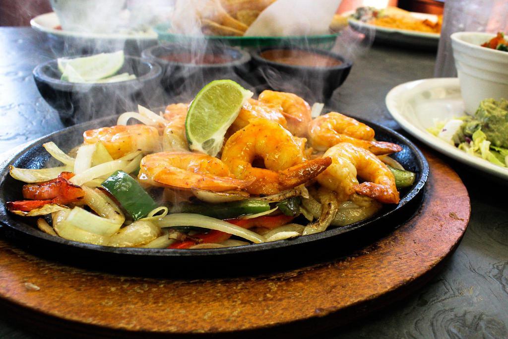 Shrimp Fajitas · Our famous fajitas are served with sauteed onions, bell peppers and tomatoes on a sizzling plate. Served with lettuce, guacamole, pico de gallo, sour cream, rice, beans and tortillas.