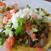 Chopped Steak Tostada · Flat fried tortilla topped with beans, lettuce, diced onions and tomatoes, shredded cheese a...