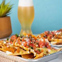 Nachos · House-made corn chips dusted with tajín, topped with cheese sauce, chorizo refried beans, pu...