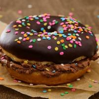 Chocolate Birthday Cake Party Bagel · Donut sliced and iced in the middle with chocolate buttercream frosting and topped with choc...