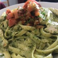 Chicken Pesto Pasta · Sliced grilled chicken tossed in a pesto sauce on a bed of fettuccine pasta, topped with a t...