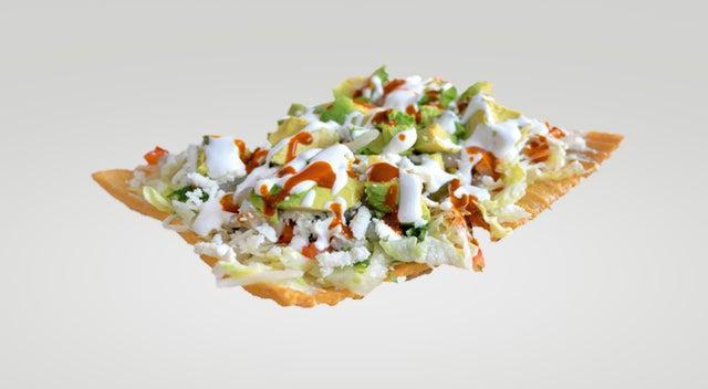 Chilindrina · Fried wheat cracker topped with pickled pig skins, cabbage, cucumbers, tomatoes, jicama, avocado, crema, Valentina, and cotija cheese