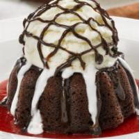 Gooey Chocolate Brownie Cake · Indulgent chocolate brownie cake and hot fudge topped with vanilla ice cream and berry sauce.