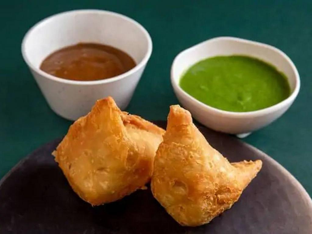 Samosas · Flaky puff pastry filled with spiced potatoes and peas, with tamarind and cilantro chutneys (2 Samosas)