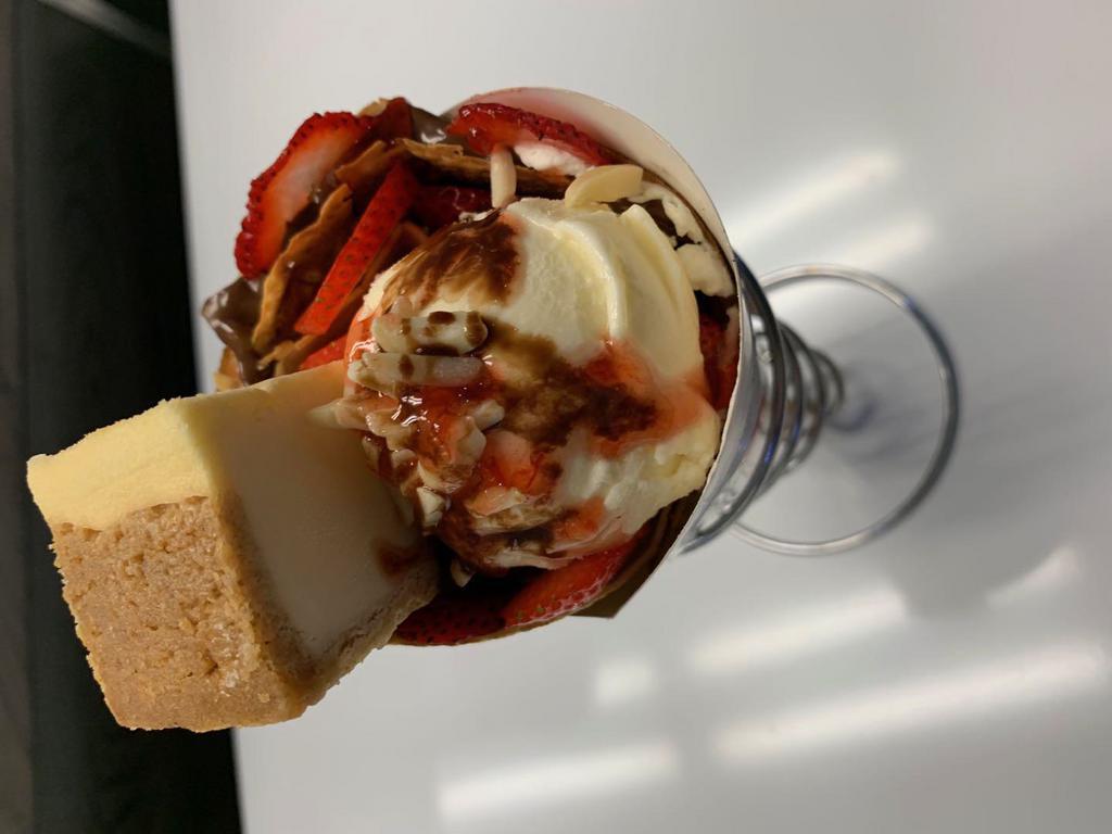 Cheesy Volcano · Cheese cake, vanilla ice cream, strawberry, almond, nutella, whipped cream, strawberry syrup, chocolate syrup