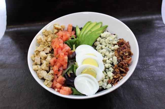 Cobb Salad · Chicken breast, avocado, crispy bacon, chopped hard-boiled egg, crumbled bleu cheese, and diced tomato are featured on a bed of mixed greens and your choice of side dressing.