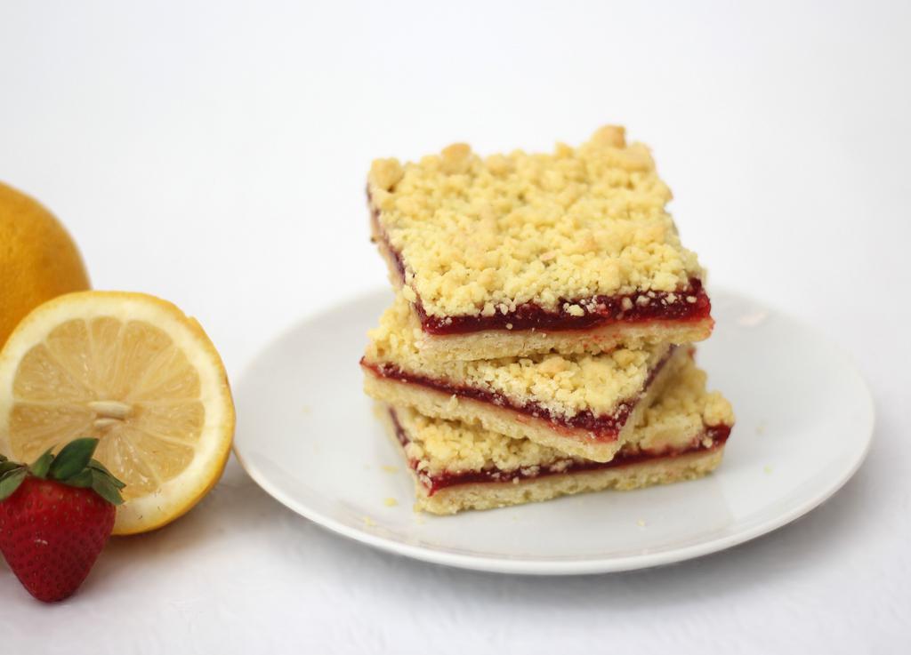Strawberry Lemon Bar · Tart, sweet and memorable strawberry sandwiched between lemon butter shortbread. Box of 12 bars. Baked in a facility that uses dairy, nuts, and wheat products.
