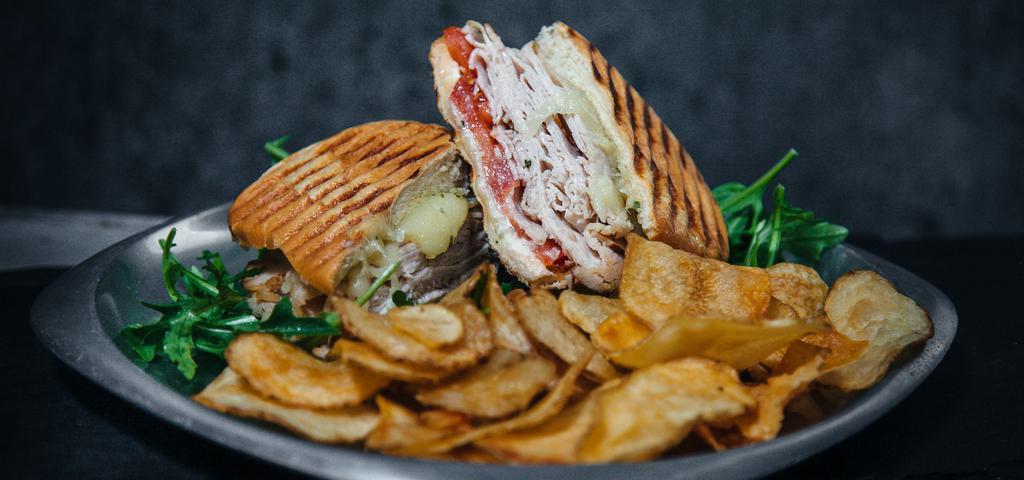 Turkey & Swiss Panini · Sliced whole breast turkey, Swiss cheese, Basil Pesto, and mayo on fresh grilled ciabatta bread with house-made potato chips. Comes with a side of spicy brown mustard.