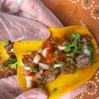 Birria Tacos · Slowly cooked tender beef sits inside a corn tortilla topped with onions, cilantro red or gr...