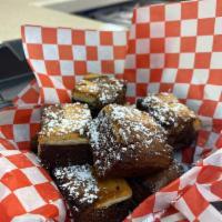 Brownie Cheesecake Bites · 8-pack of brownie cheesecake bites topped with powdered sugar.