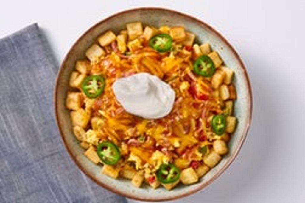 Southwestern Spicy Bowl · Let's spice it up! Seasoned country potatoes, topped with scrambled eggs mixed-in with sautéed diced red and green peppers, chorizo, and carnitas, topped with ranchero sauce and shredded cheddar cheese and finished with sour cream and jalapeno slices.
