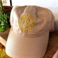 Hat · Classic dad hat in a neutral tan color with our 'Keep Your Chin Up' badge design in gold thr...
