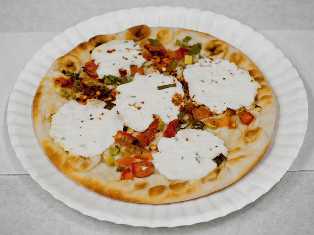 Goat Cheese Manakish · Pita dough pizza topped with Napa Hill goat cheese, green onions, chopped tomatoes, pepper flakes and olive oil. Vegetarian.