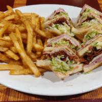 Triple Turkey Club Sandwich · Sandwiches are served with lettuce, tomato and French fries.