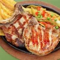 79. Chuletas a la Parrilla · Grilled pork chops, fried green plantain & rice.