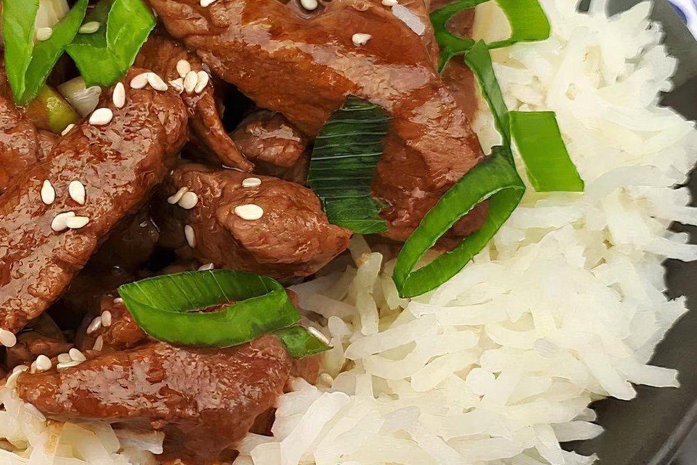 Beef over Rice · Pan seared thinly sliced strips of seasoned beef served over a bed of jasmine rice.  Garnished with green onions, sesame seeds, and savory soy sauce.