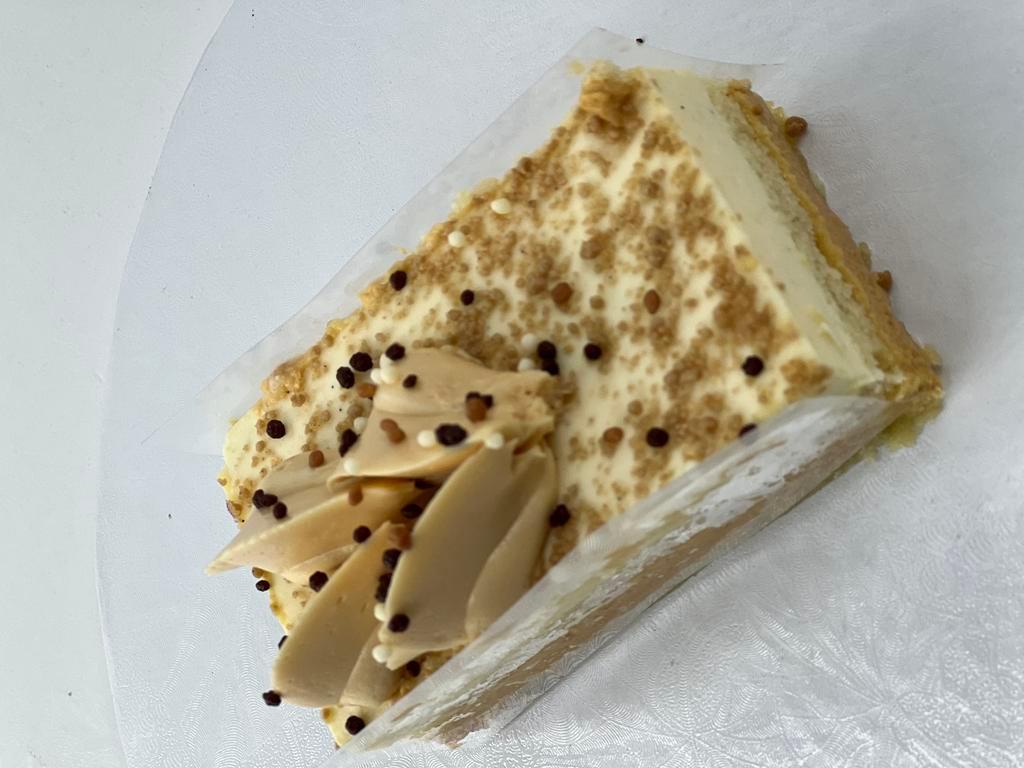 New Vanilla Creme Brulee Cake · A toasty caramel mousse layered between sponge cake and topped with rich vanilla Bavarian cream and a toasted graham cracker crumb topping. A thin layer of white chocolate coats the bottom for moisture resistance.