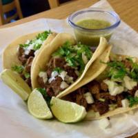 Flank Steak Tacos · 3 Flank steak tacos served with chopped white onions, cilantro, lime wedges, and salsa verde...