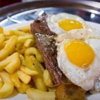 Bife a lo Pobre · Savory Ribeye Steak, two fried eggs, french fries and caramelized onions.