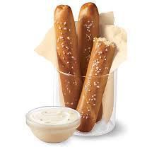 Soft Pretzel Sticks · Soft pretzel sticks, served hot from the oven, covered in butter and salt, served with warm zesty queso dipping sauce.