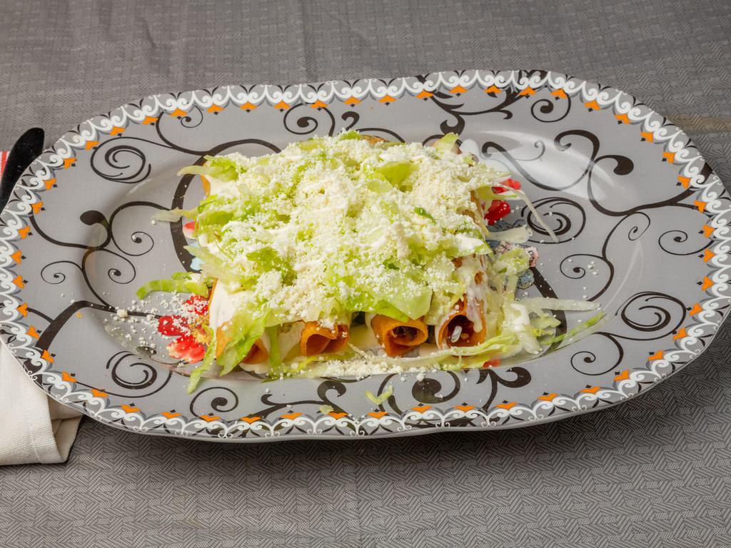 Flautas de birria · fried corn tortilla filled with shredded beef, served with lettuce, mexican cream and cotija cheese