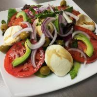 Mozzarella Caprese Salad · Fresh mozzarella, tomatoes, avocado, red onion, basil and olives on a bed of mixed greens to...