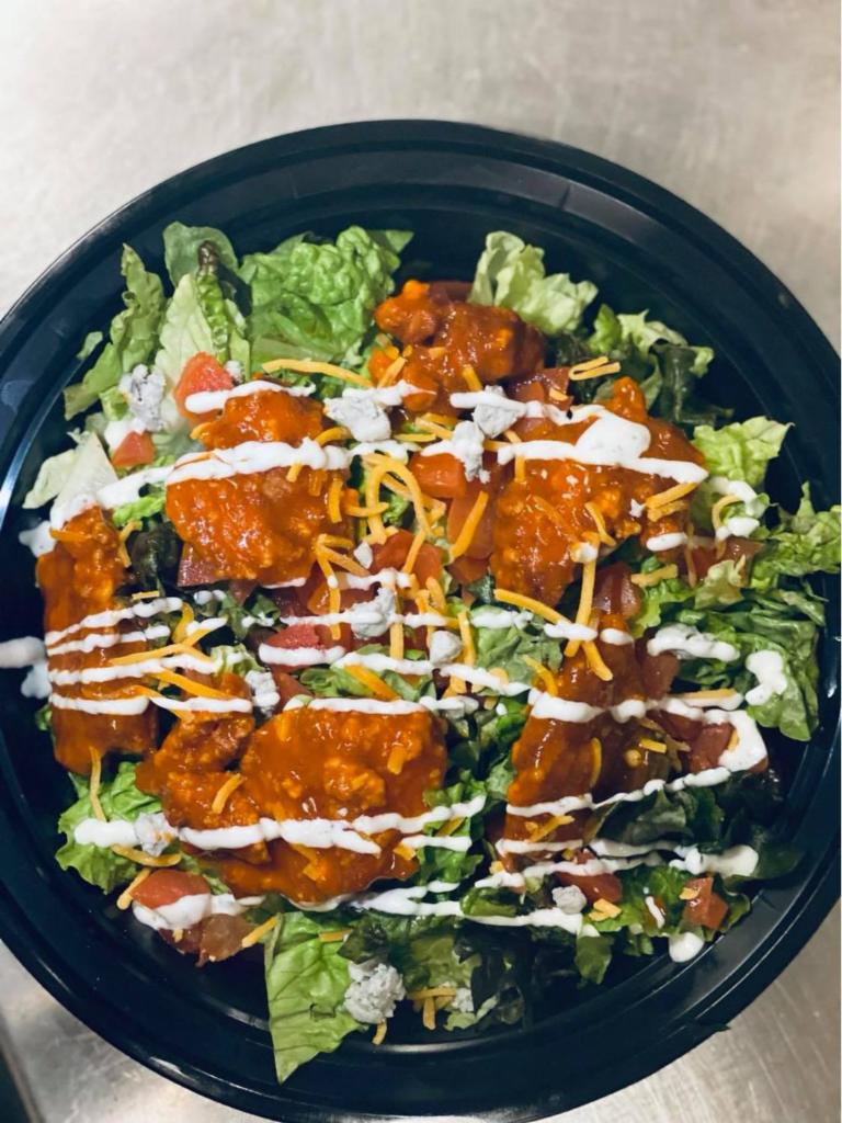 Buffalo Wing Salad · All white meat  Boneless Wings with Buffalo Sauce on a bed of lettuce tomatoes Blue Cheese Crumbles shredded Cheddar Cheese and a side of Ranch.