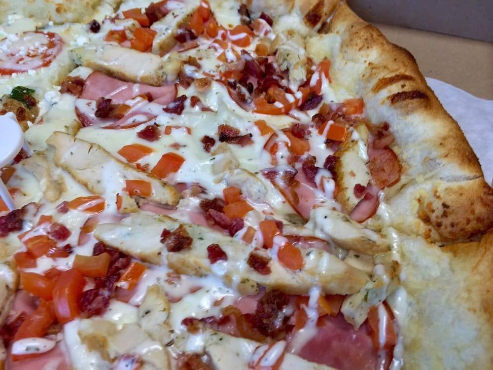 Chicken Bacon Ranch Pizza · Garlic chicken, bacon crumbles, Canadian bacon & cooked tomatoes atop a ranch base; finished with a drizzle of ranch on top.