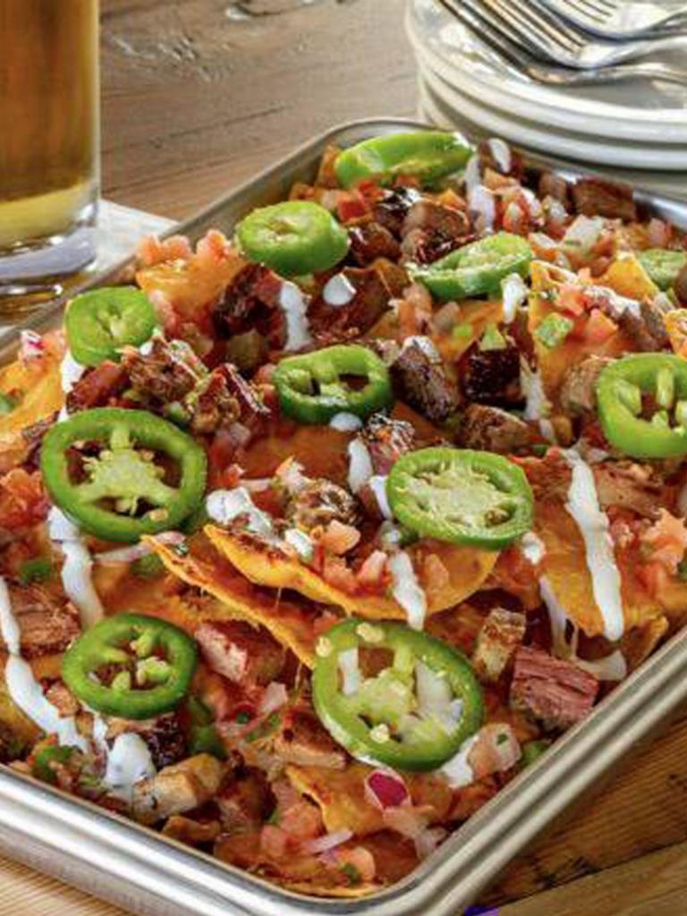 Brisket Nachos · Stacked and loaded with beef brisket, cheddar jack cheese, Pale Ale Queso, lime sour cream, pico de gallo and fresh jalapeños
