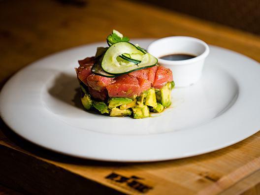 Ahi Tuna Tower · Our chef's creation, a sushi grade ahi tuna marinated in a house made ponzu sauce topped with cucumber noodles, fresh avocado and a drizzle of chipotle aioli, served with home-made tostadas.