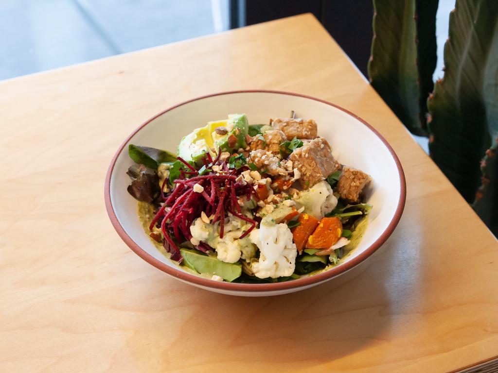Kind Cartel Hot Bowl · Maple roasted carrots and cauliflower, garlic herb tahini sauce, steamed kale and brown rice, avocado, mixed greens, ginger sesame marinated tempeh, beet, crushed almonds, and hemp seeds.