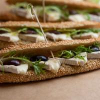 Brie & Olive Sandwich on Breads Jerusalem Baguette · Brie, kalamata olives and frisébe on a Breads Jerusalem Baguette.