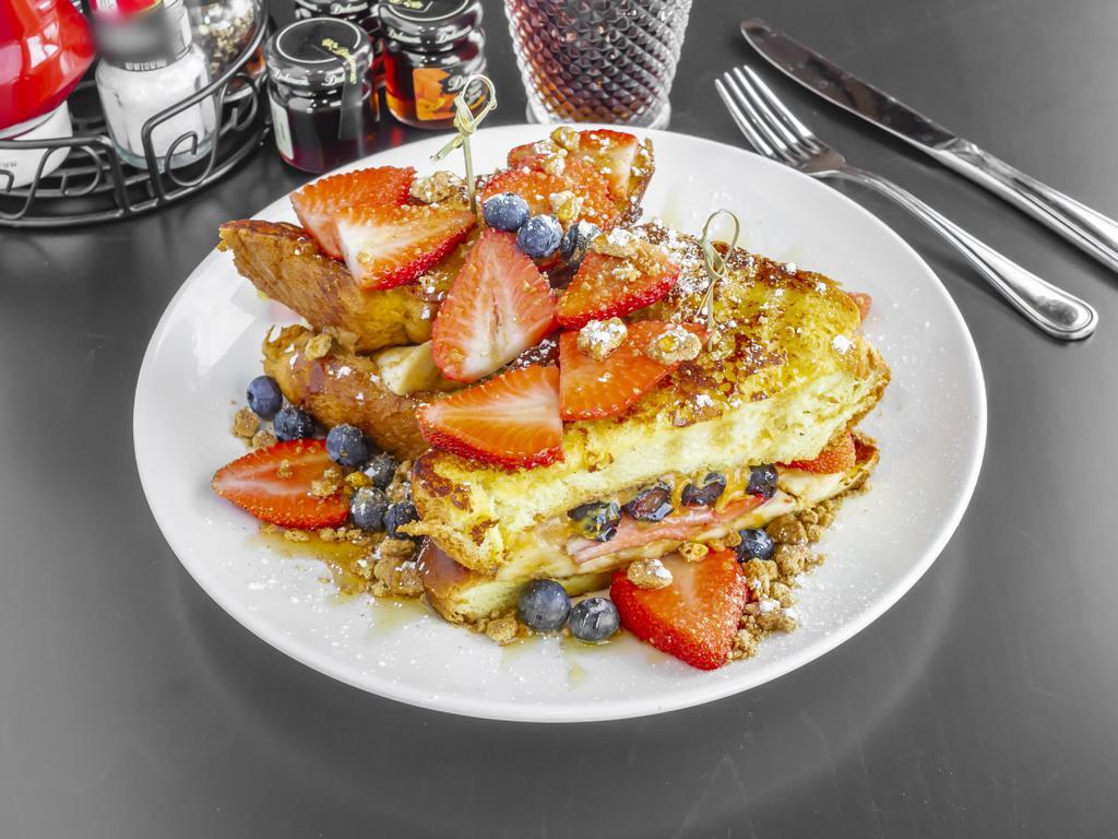 French Toast Sandwich · Stuffed with peanut butter and banana, topped with fresh berries and graham cracker, drizzled with honey.