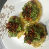 Tostones with guacamole and chorizo · 3 fried green plantains topped with guacamole, cilantro, chorizo and limes.
