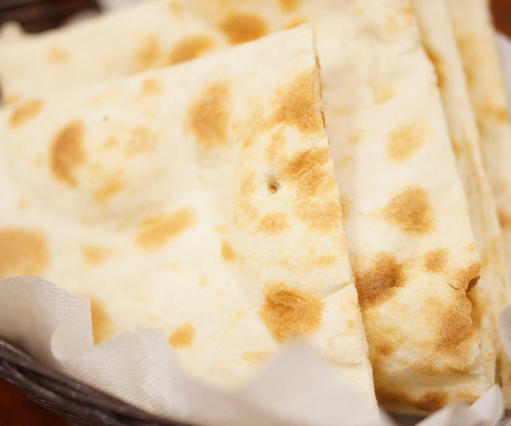 Plain Naan · Flat and soft bread made of white flour and baked in the clay oven. 