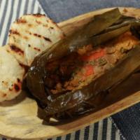Tamal con Arepa · Cornmeal filled with chicken, pork, potatoes, carrots, and peas all wrapped in a banana leaf...