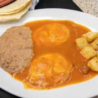 Huevos Rancheros · 2 over easy eggs with rancheros red sauce, potatoes and refried beans.