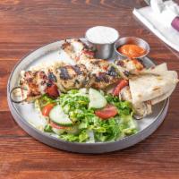 Chicken Skewers · Grilled marinated chicken cubes with onions and peppers, served with rice and salad.