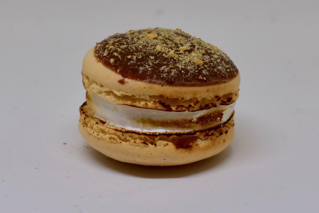 S'Mores Macaron · Caramel flavored shell with milk chocolate disk, marshmallow, and graham cracker cookie crumbs (contains gluten).