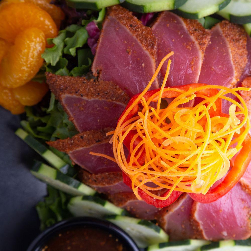 Seared Tuna Tataki Salad · Seared sashimi grade tuna over a bed of crisp mixed greens served with cucumbers and crispy wontons with soy ginger dressing.