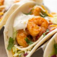 Exotic Shrimp Taco · succulent sauteed shrimp over a bed of garlic cilantro lime slaw and topped with cojita cheese
